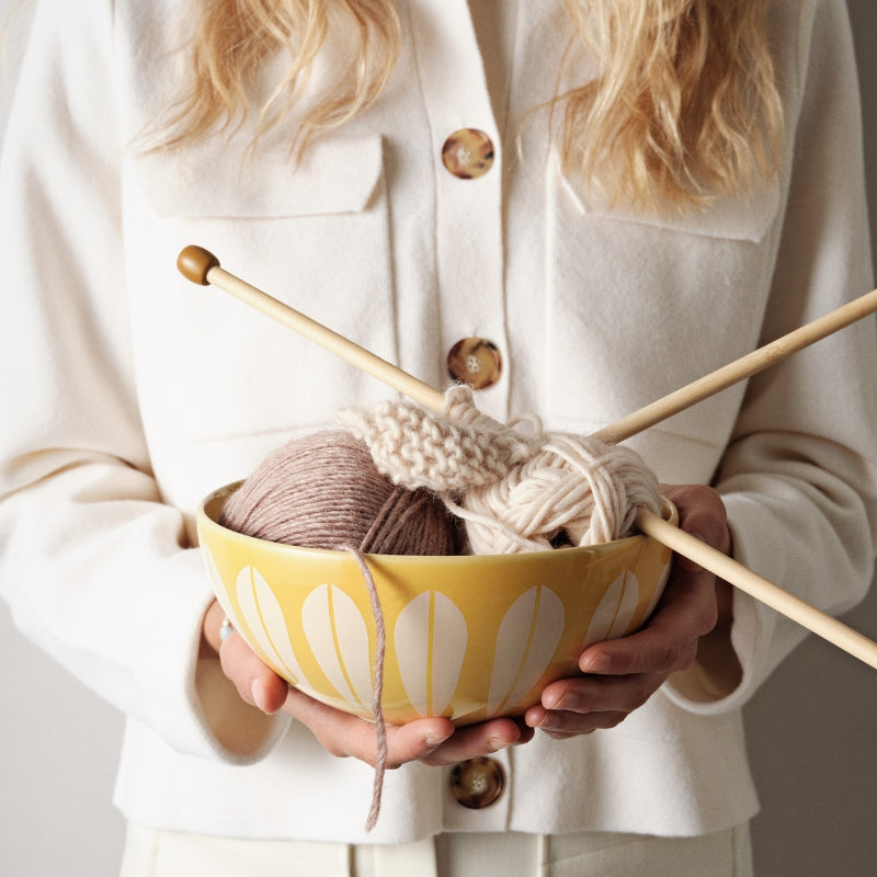 Woman holding yarn and needles with Arne Clausen's 'Lotus' pattern.