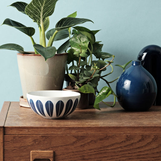 Wooden dresser with vase of plants, featuring servingware with iconic ‘Lotus’ pattern by Arne Clausen.
