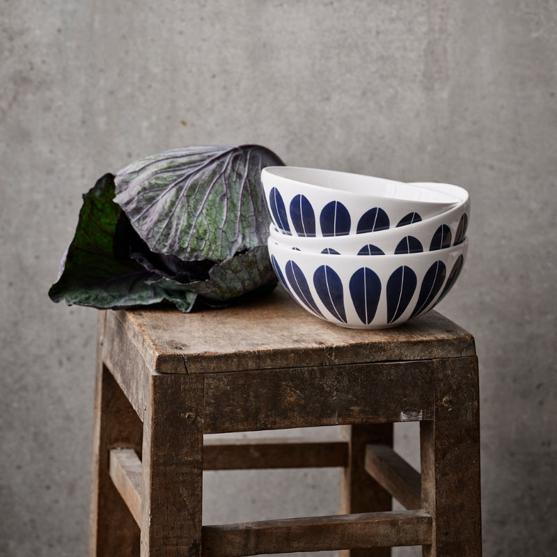 A wooden stool with a bowl and cabbage on it. The bowl features the iconic ‘Lotus’ pattern by Arne Clausen.