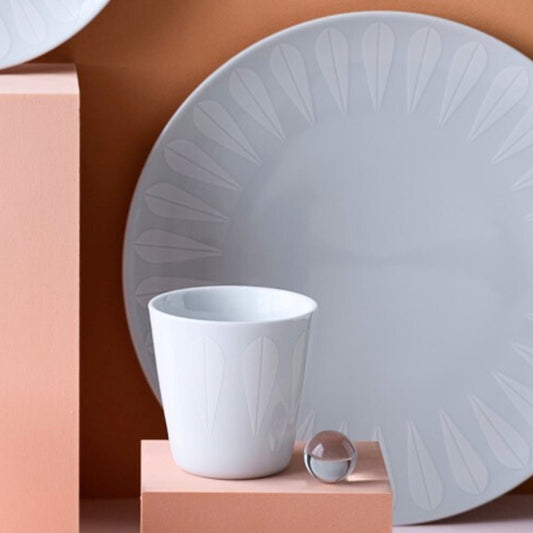 Lotus pattern plate and cup on pink surface.