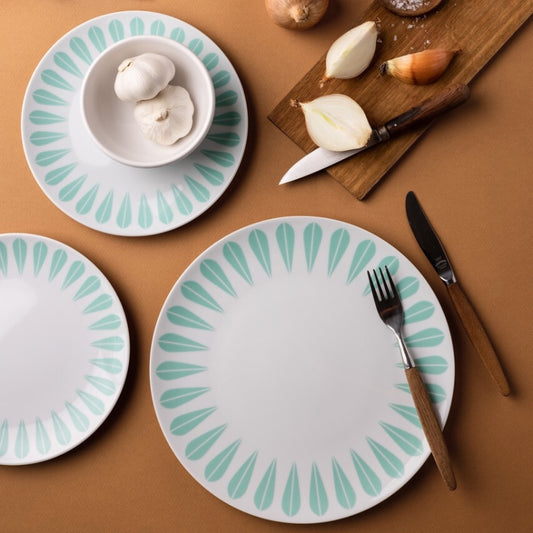 A table set with four plates, a knife, and a fork. The plates and servingware feature the iconic 'Lotus' pattern by Arne Clausen.